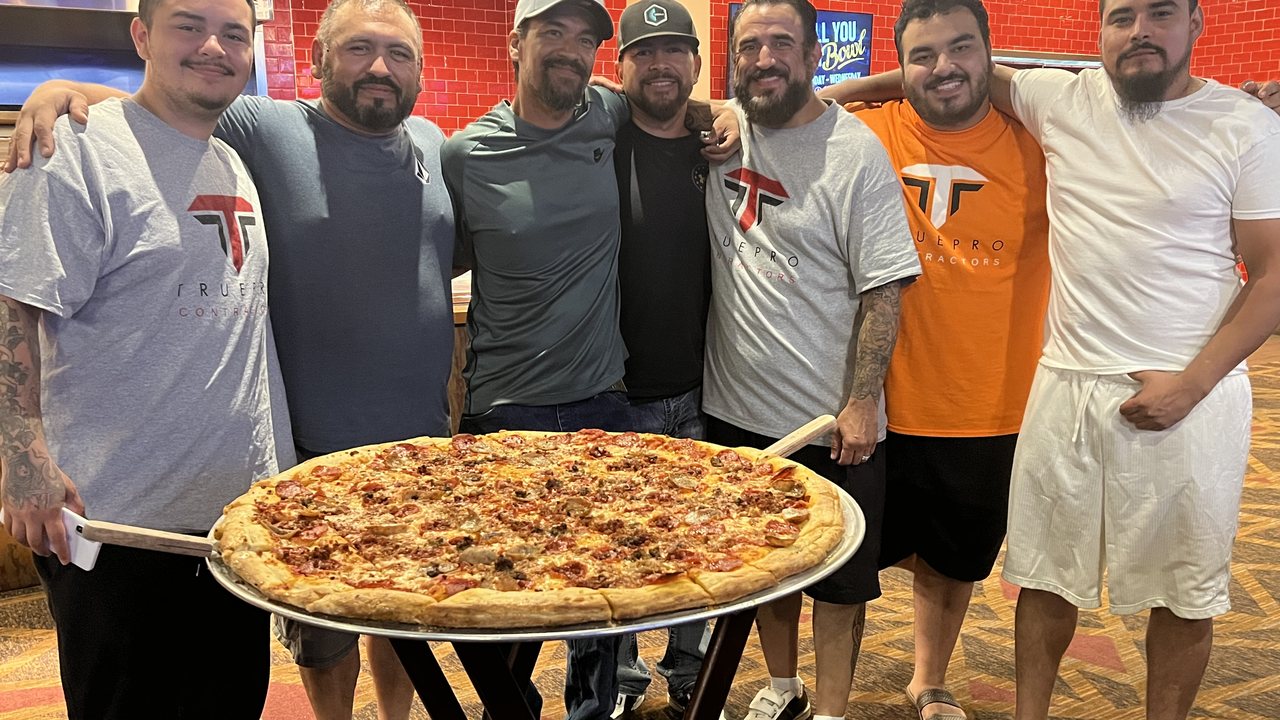 TruePro crew together around a large pizza